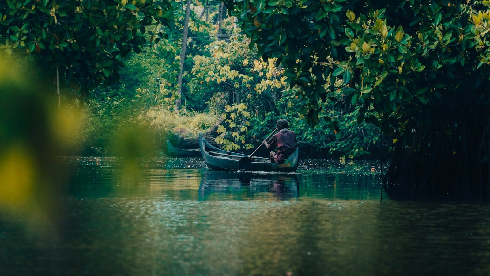 Person paddling a small boat on calm water