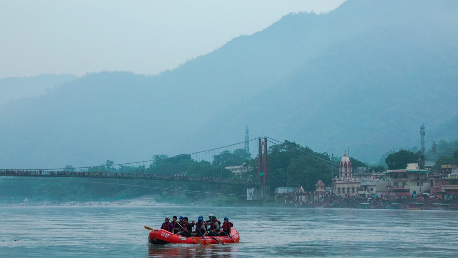 Group rafting through river rapids wearing helmets and life jackets